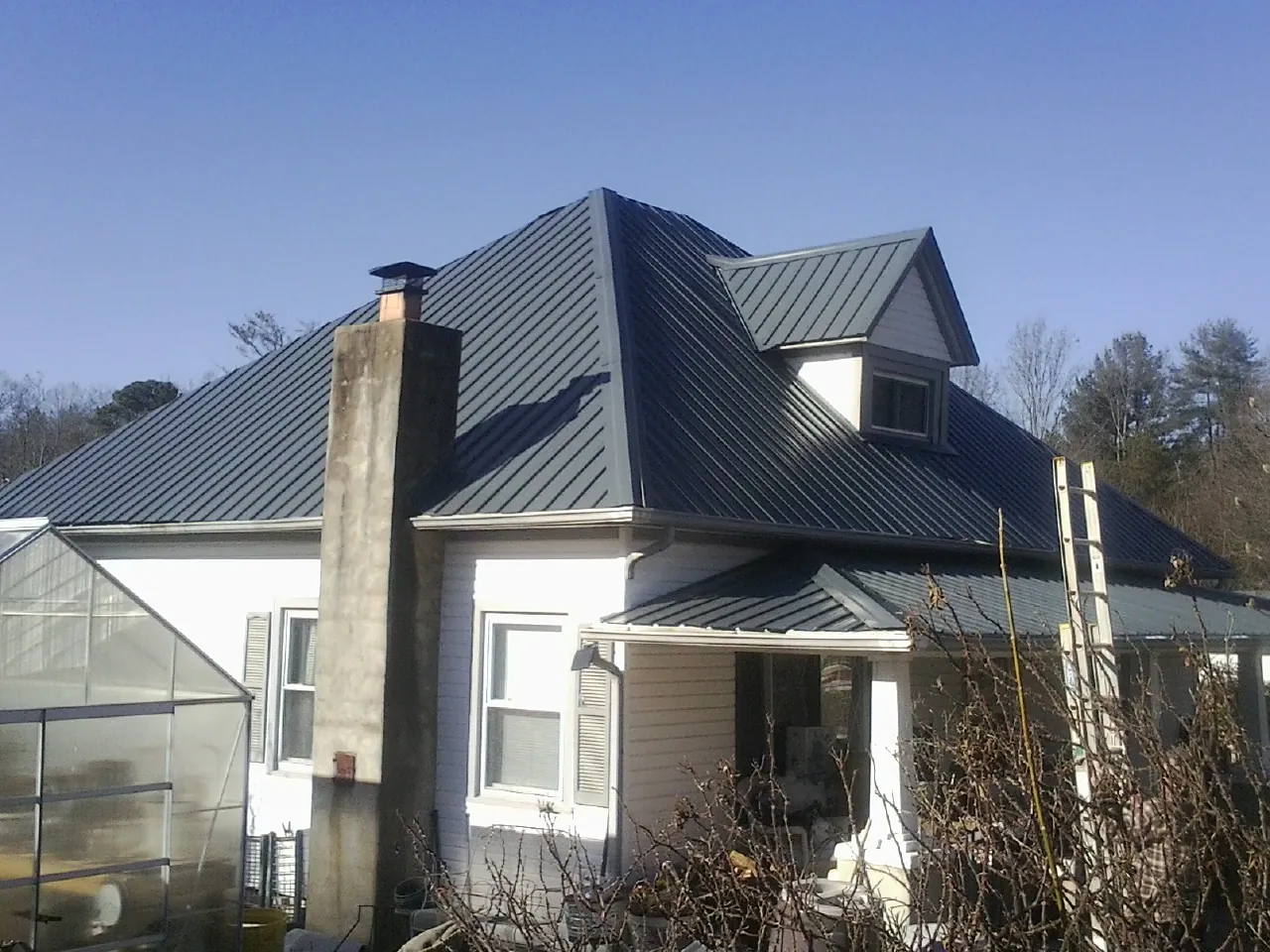 Dark blue standing seam metal roof on a white farmhouse with dormer — Slate & Tile Roof Repair by Roofing Brothers in Mountain Top