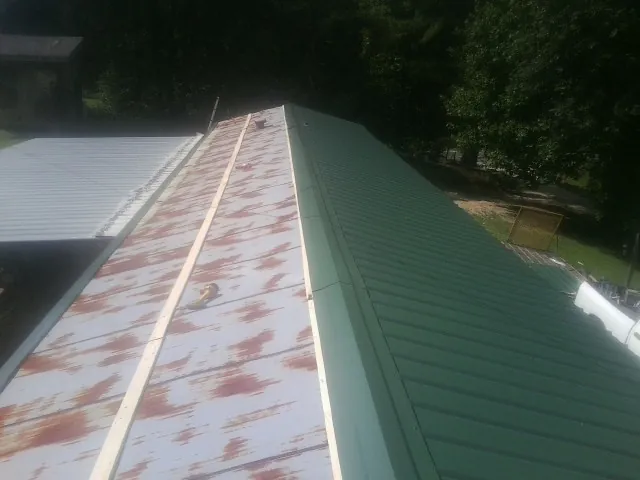 Old rusted panels beside newly installed green metal roofing — Wind Damage Roof Repair by Roofing Brothers in Mountain Top