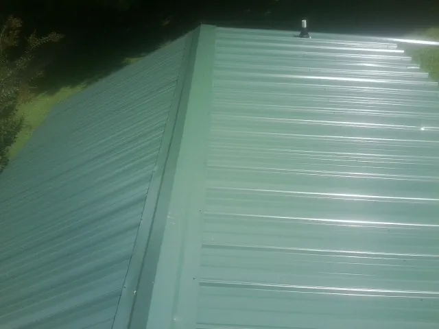 New green metal panels meeting at the ridge of a roof — Flat Roof Repair work by our crew in Mountain Top