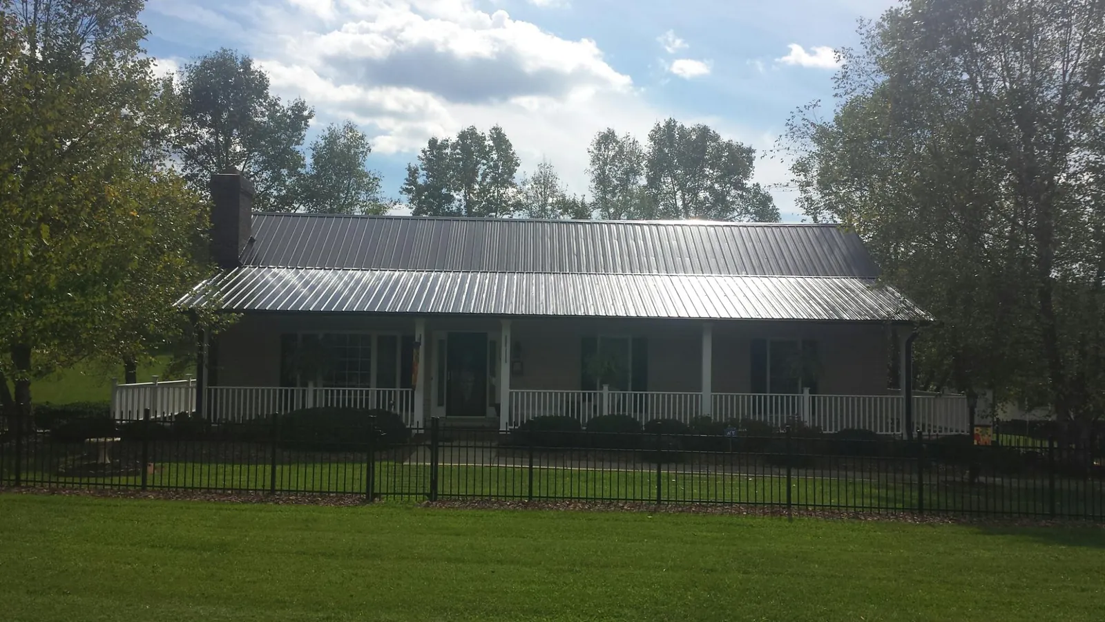 Gray metal roof on a brick ranch with a full width front porch — Gutter Guard Installation work by our crew in Mountain Top