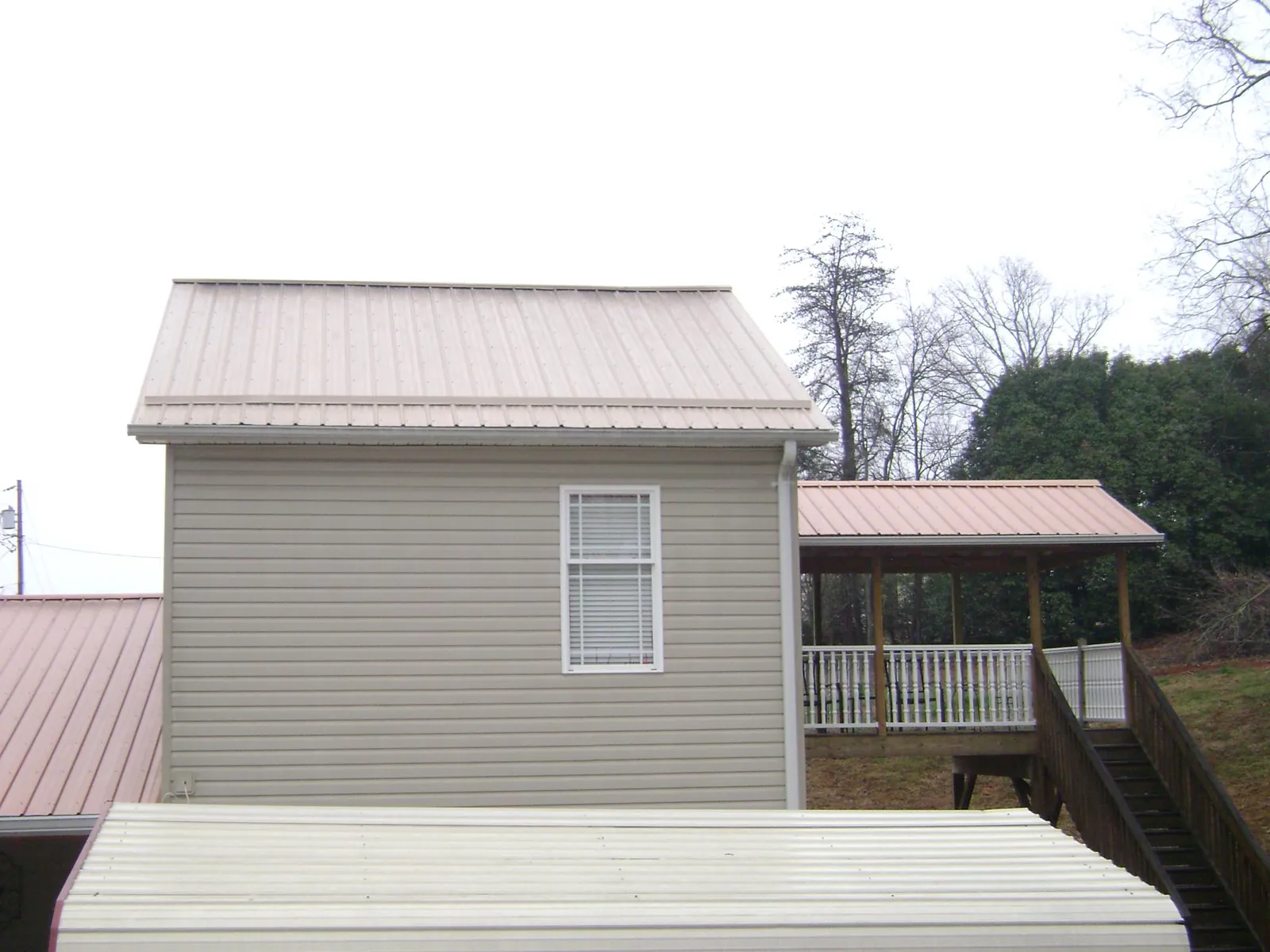 Tan metal roofs on a two story addition and attached porch, from a Roof Replacement job in Mountain Top