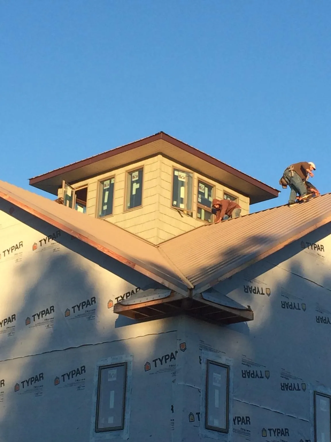 Roofers working around a rooftop cupola on a new metal roof at sunset — Roof Waterproofing in Mountain Top by Roofing Brothers